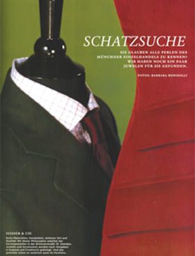 © Seisser & Cie. Muenchen GmbH Eine dunkle Schaufensterpuppe trägt auf der linken Seite eine grüne Anzugsjacke, ein weißes Hemd und eine rote Krawatte. Auf der rechten Seite ist ein Teil eines roten Kleides zu sehen. Oben erscheint ein deutscher Text, darunter das Wort "SCHATZSUCHE".
