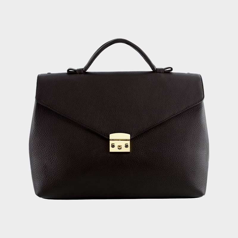 Eine schwarze Lederhandtasche mit strukturierter Oberfläche, oberem Henkel und einem goldenen Verschluss vor einem schlichten hellgrauen Hintergrund.