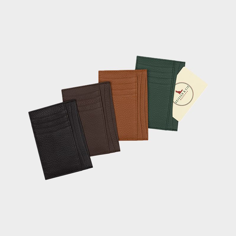Vier Kartenhalter aus Leder in den Farben Schwarz, Dunkelbraun, Hellbraun und Grün, nebeneinander angeordnet, wobei der grüne Kartenhalter eine Karte enthält, die teilweise sichtbar ist.